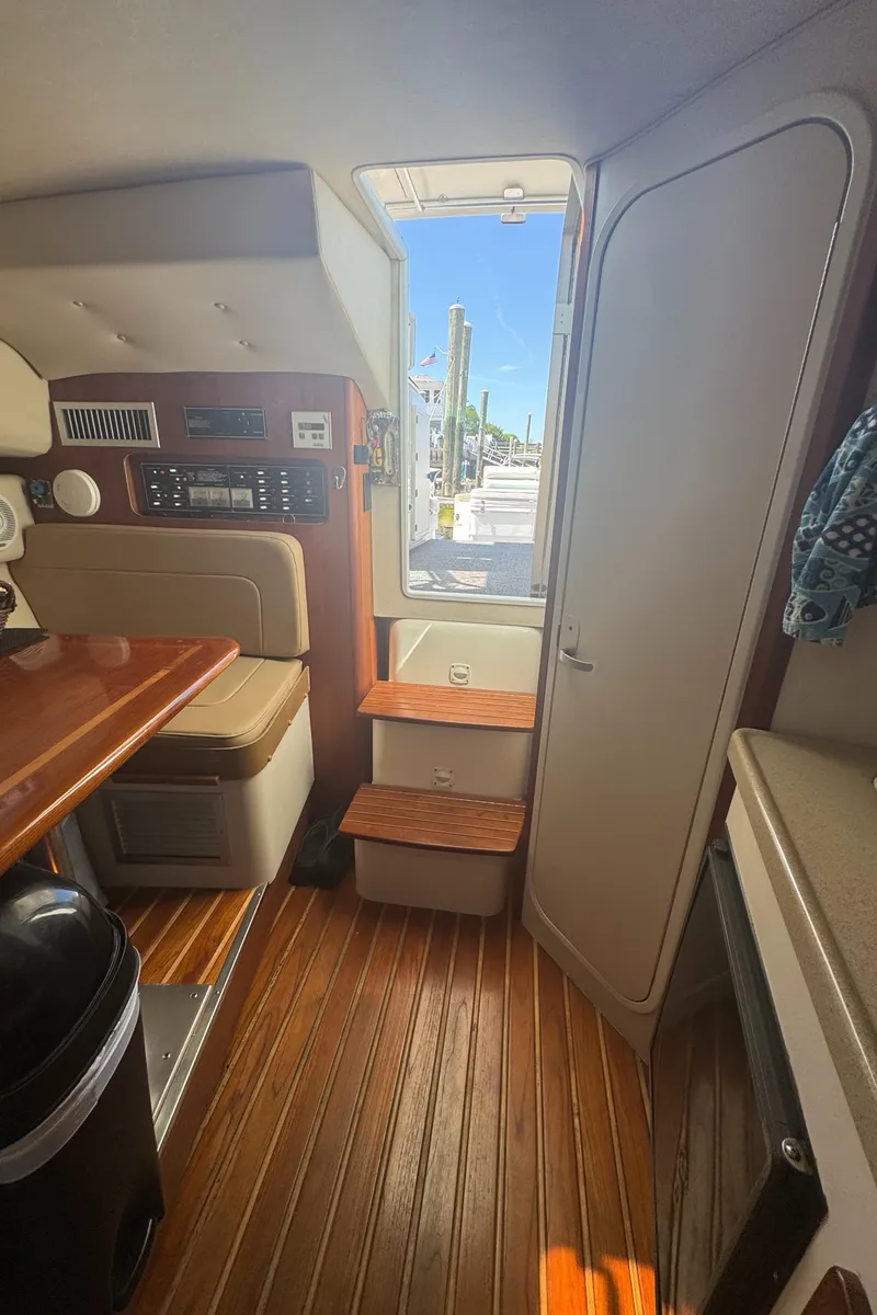 Slide: The Image of Interior of a 2002 Pursuit 3000 Express boat with wooden flooring and seating. - 28