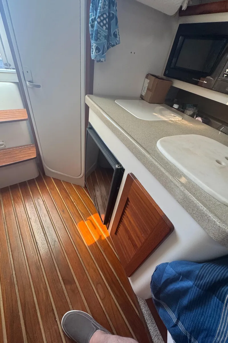 Slide: The Image of Interior of a 2002 Pursuit 3000 Express boat with wooden flooring and kitchenette. - 29