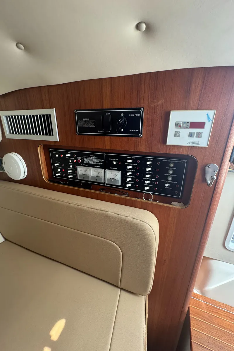 Slide: The Image of Control panel inside 2002 Pursuit 3000 Express boat, featuring switches and gauges on wooden panel. - 30