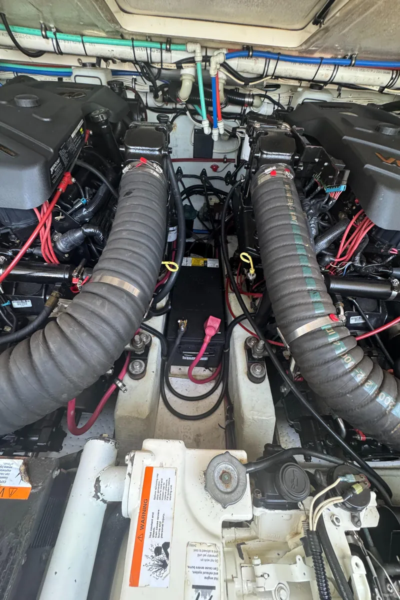 Slide: The Image of Engine compartment of a 2002 Pursuit 3000 Express boat, featuring dual engines and wiring. - 37