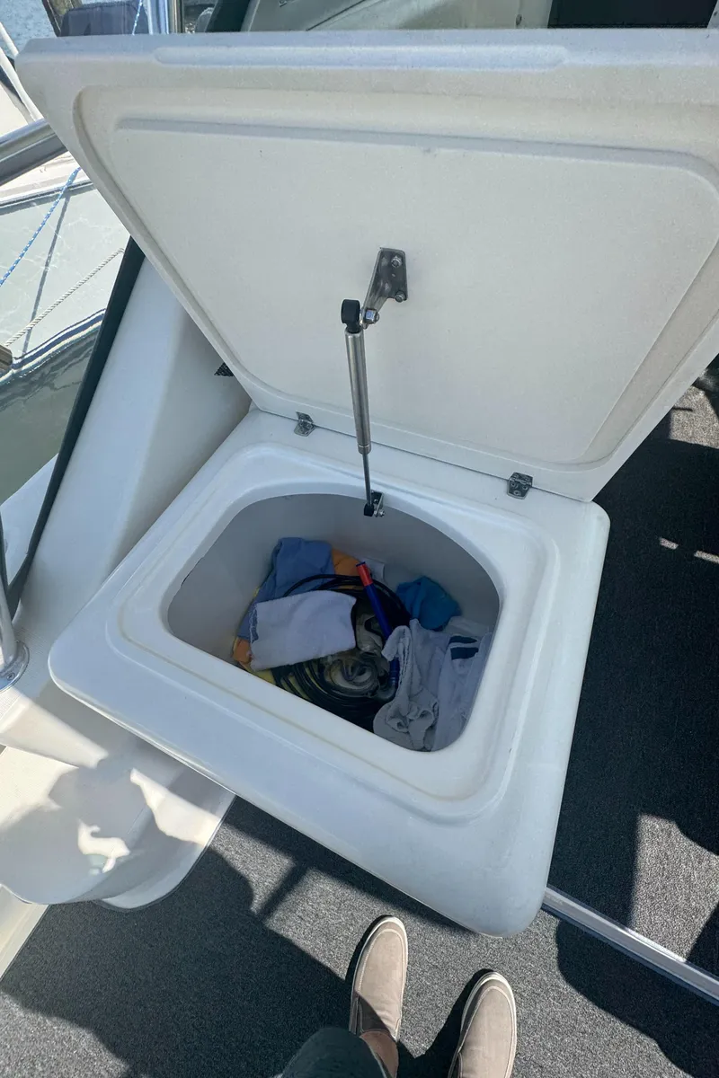 Slide: The Image of Open storage compartment on 2002 Pursuit 3000 Express boat with clothes inside. - 41