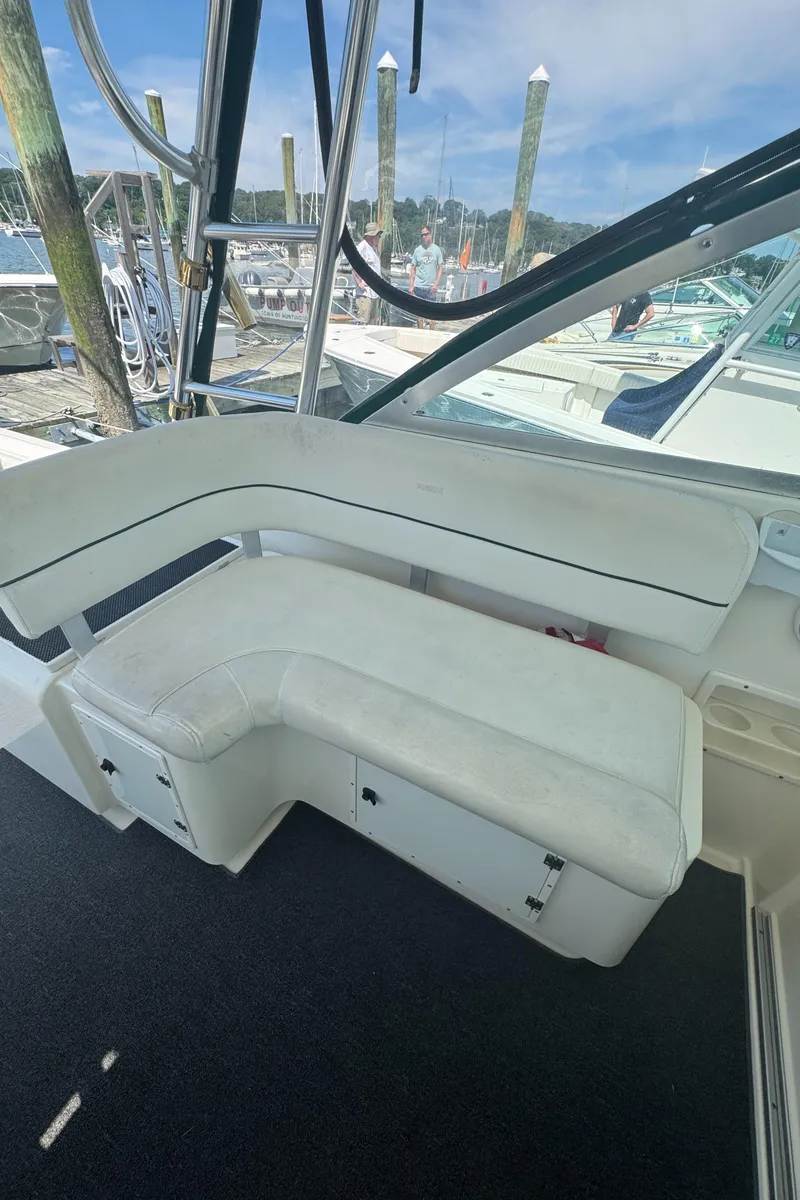 Slide: The Image of 2002 Pursuit 3000 Express boat interior with white seating and marina background. - 42