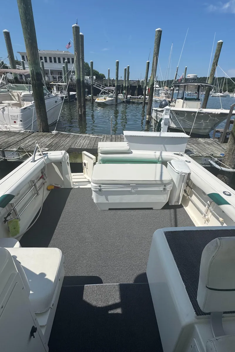 Slide: The Image of 2002 Pursuit 3000 Express boat docked at marina, featuring spacious deck and seating area. - 6