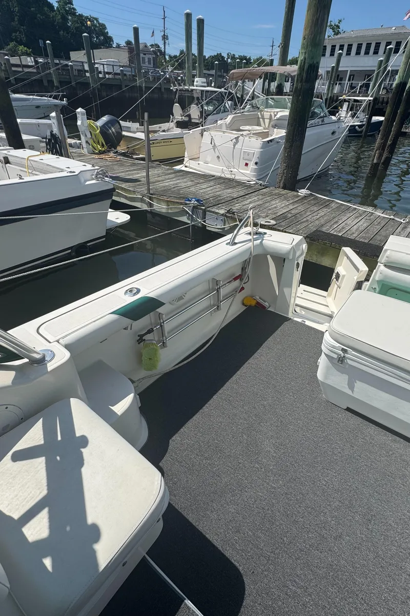 Slide: The Image of 2002 Pursuit 3000 Express boat docked at marina, featuring spacious deck and seating. - 7