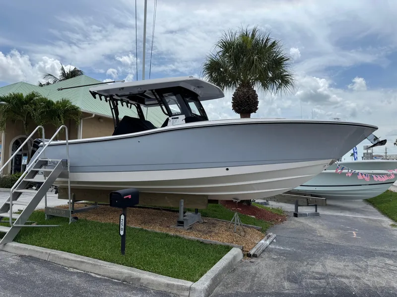 Slide: The Image of 2025 Robalo R300 Center Console boat displayed outdoors with palm trees and a cloudy sky. - 1