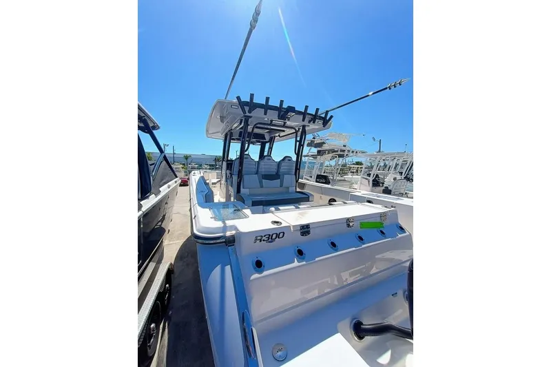 Slide: The Image of 2025 Robalo R300 Center Console boat with sleek design, docked under clear blue sky. - 9