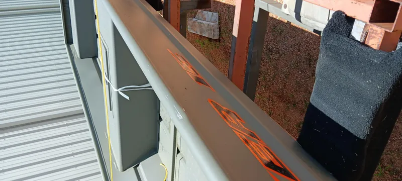 Slide: The Image of Tracker 1542 JON boat, 2026 model, with orange decals, stored on a metal rack. - 10