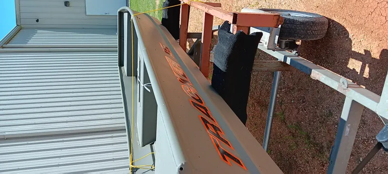 Slide: The Image of Tracker 1542 JON boat on trailer near metal building, 2026 model. - 11