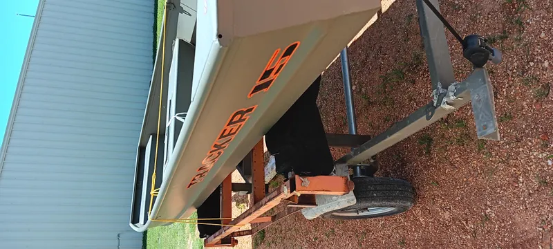 Slide: The Image of 2026 Tracker 1542 JON boat on trailer, parked on gravel near a building. - 12