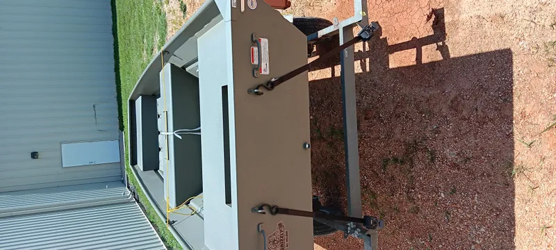 Slide: The Image of 2026 Tracker 1542 JON boat on trailer, parked on gravel near a building. - 13