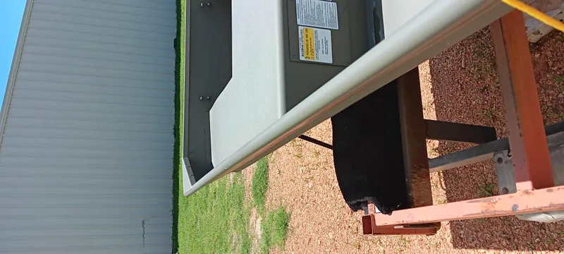 Slide: The Image of 2026 Tracker 1542 JON boat on trailer, side view near metal building. - 4