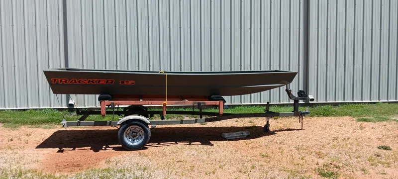 Slide: The Image of 2026 Tracker 1542 JON boat on trailer, parked outdoors near metal building. - 9