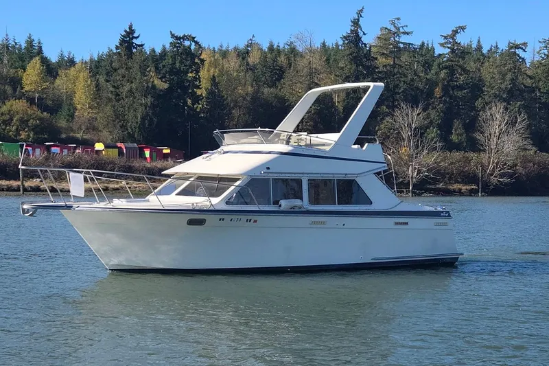 Slide: The Image of 1990 Tollycraft Sport Sedan boat cruising on a serene lake with forested background. - 1