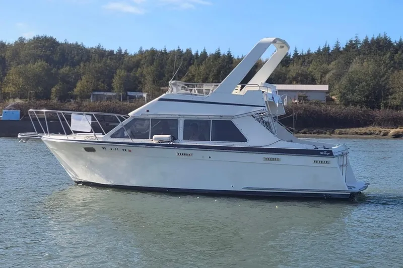 Slide: The Image of 1990 Tollycraft Sport Sedan boat on calm water, surrounded by trees. - 2