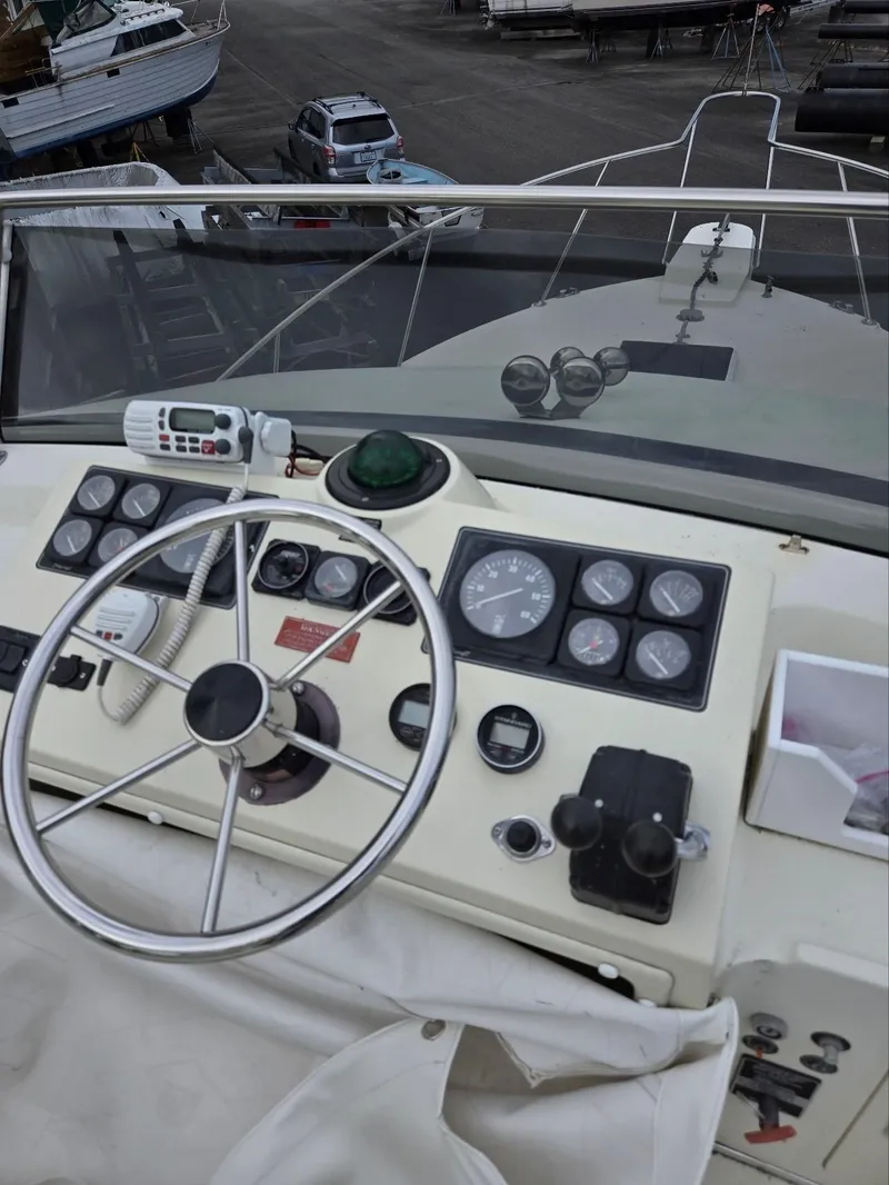 Slide: The Image of 1990 Tollycraft Sport Sedan helm with steering wheel, gauges, and marine radio. - 24