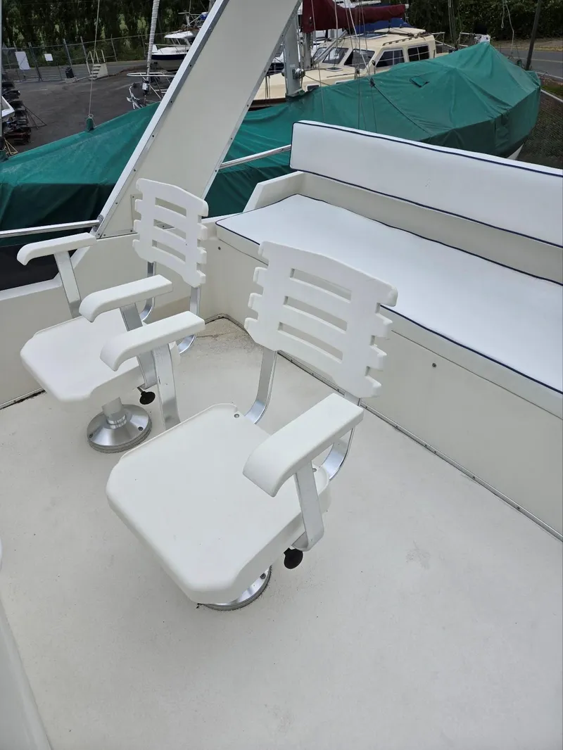 Slide: The Image of 1990 Tollycraft Sport Sedan deck with white chairs and seating area. - 25