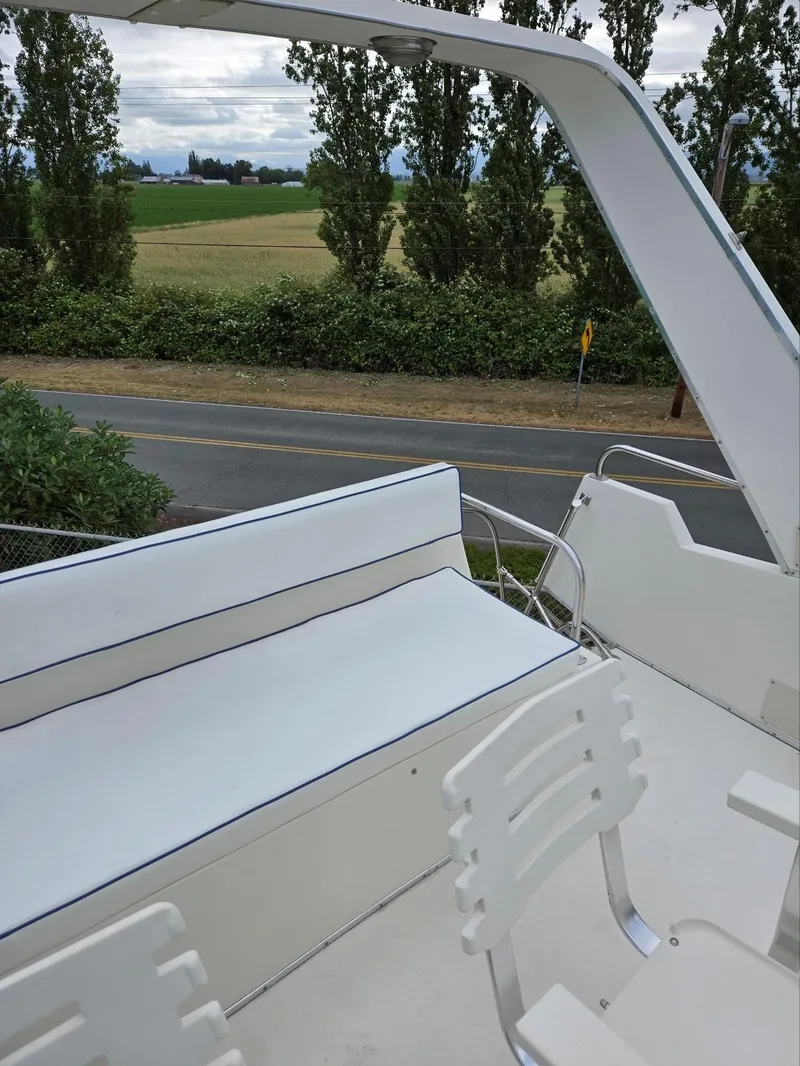 Slide: The Image of 1990 Tollycraft Sport Sedan boat interior with white seating, near a rural road and trees. - 27