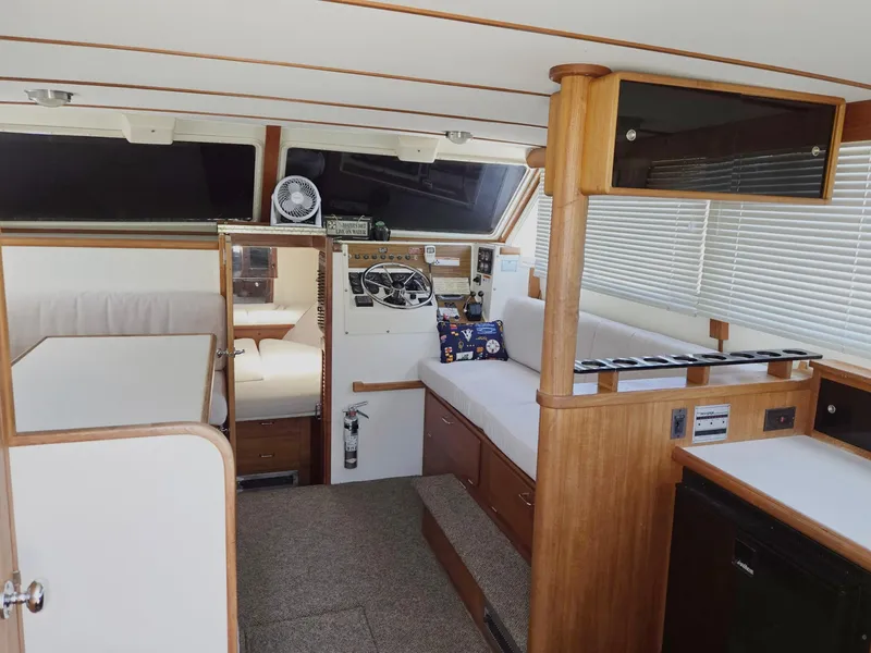 Slide: The Image of 1990 Tollycraft Sport Sedan interior with helm, seating, and wood accents. - 29