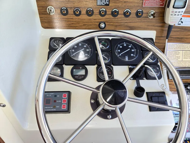 Slide: The Image of 1990 Tollycraft Sport Sedan dashboard with steering wheel and control gauges. - 31