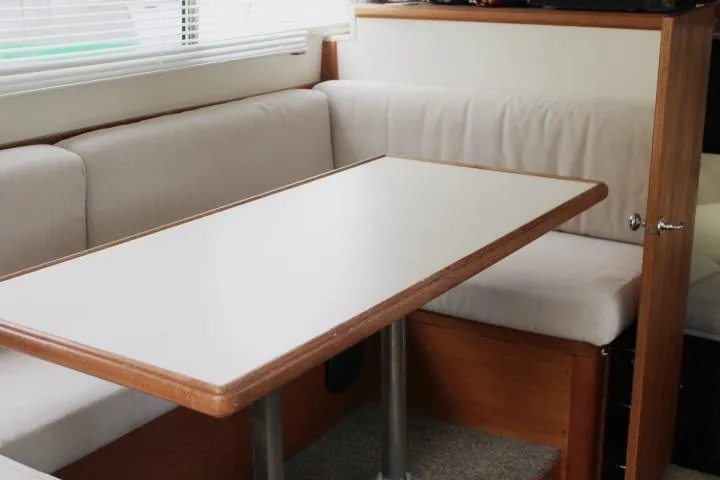 Slide: The Image of 1990 Tollycraft Sport Sedan interior with a cozy dining area and cushioned seating. - 35