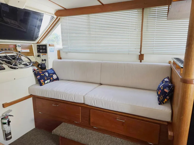 Slide: The Image of 1990 Tollycraft Sport Sedan interior with white sofa, nautical pillows, and steering console. - 36