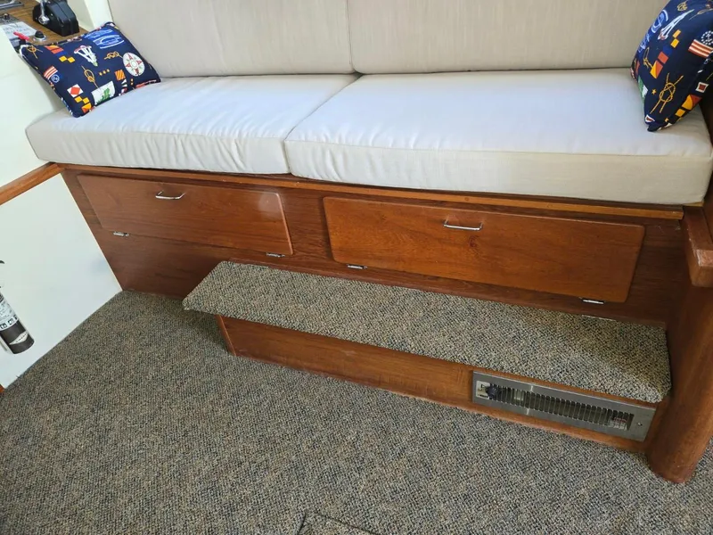 Slide: The Image of 1990 Tollycraft Sport Sedan interior with cushioned seating and nautical-themed pillows. - 38