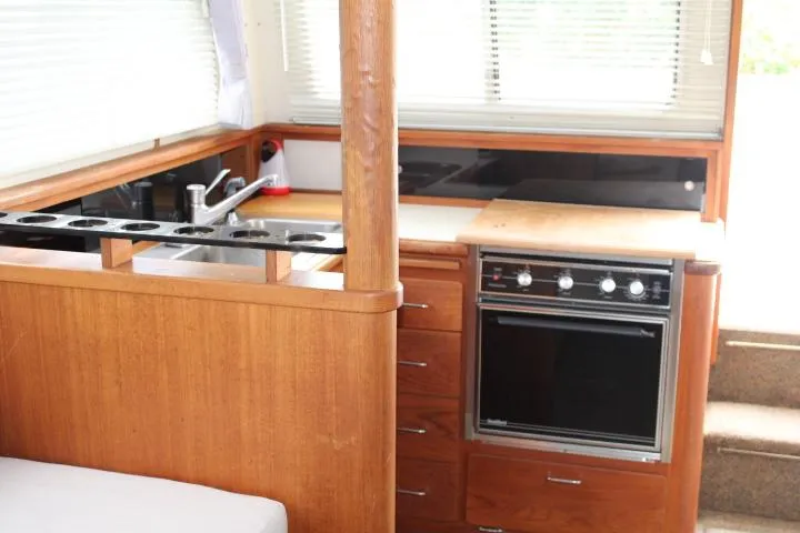 Slide: The Image of 1990 Tollycraft Sport Sedan kitchen with wood cabinetry, oven, and sink. - 41