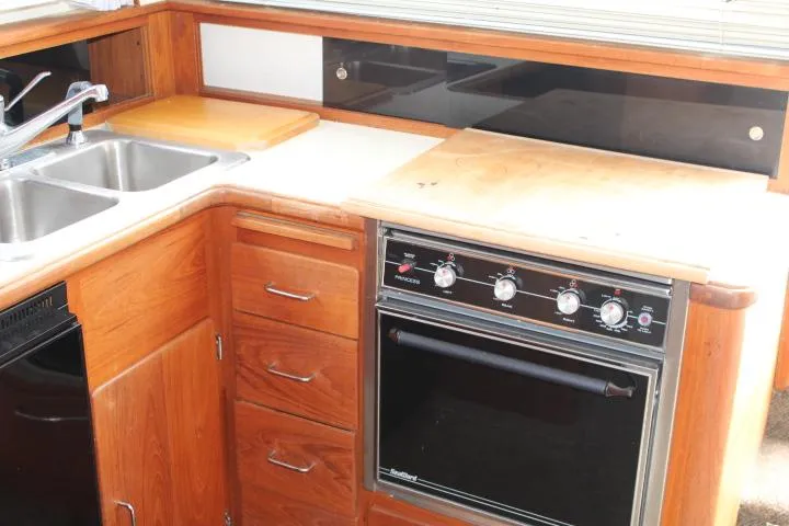 Slide: The Image of 1990 Tollycraft Sport Sedan kitchen with wooden cabinetry, double sink, and built-in oven. - 43