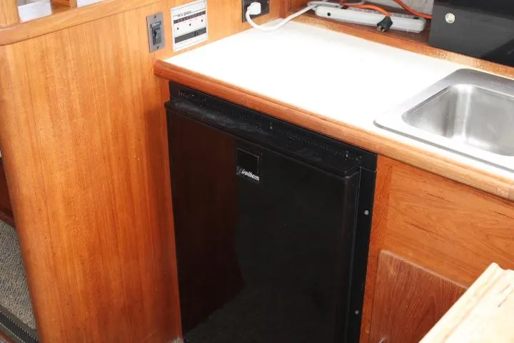 Slide: The Image of 1990 Tollycraft Sport Sedan interior with compact fridge and sink in wooden cabinetry. - 45