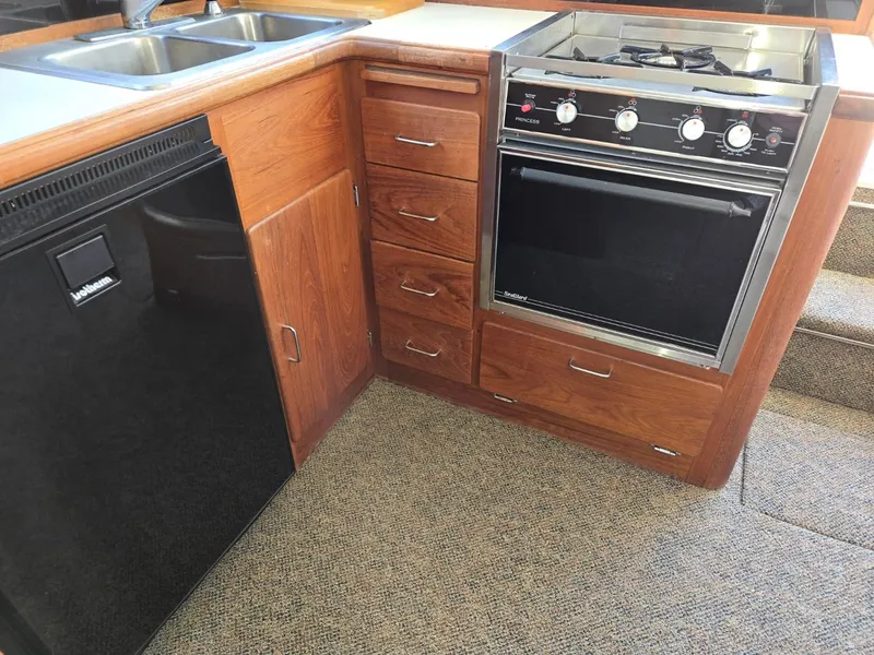 Slide: The Image of 1990 Tollycraft Sport Sedan kitchen with stove, sink, and refrigerator. - 46