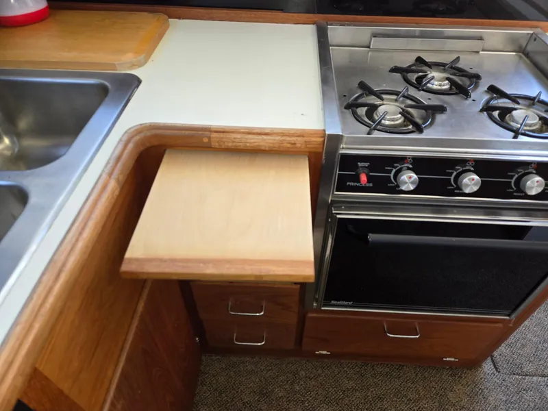 Slide: The Image of 1990 Tollycraft Sport Sedan kitchen with stove, sink, and wooden countertop extension. - 48