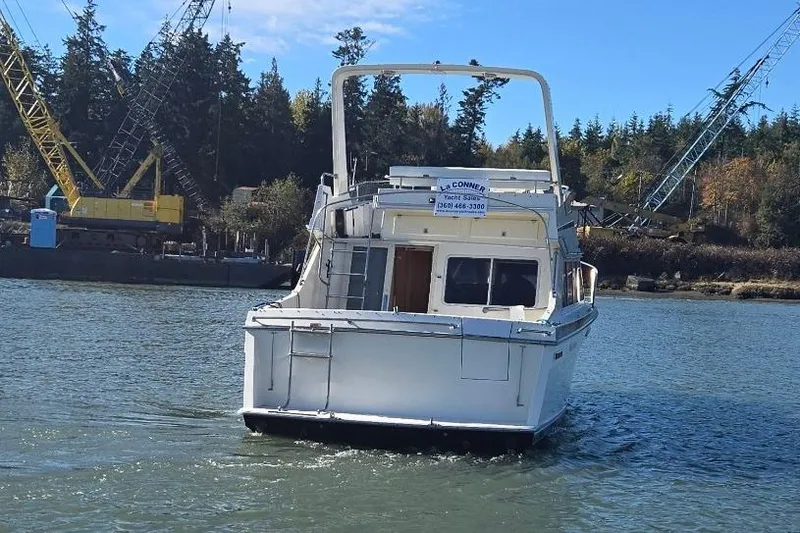 Slide: The Image of 1990 Tollycraft Sport Sedan boat on water, with cranes and trees in the background. - 5