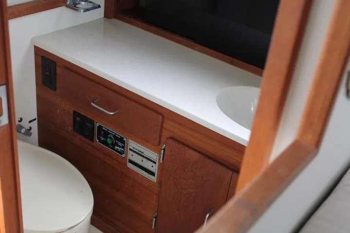 Slide: The Image of 1990 Tollycraft Sport Sedan bathroom with wooden cabinetry and white countertop. - 54