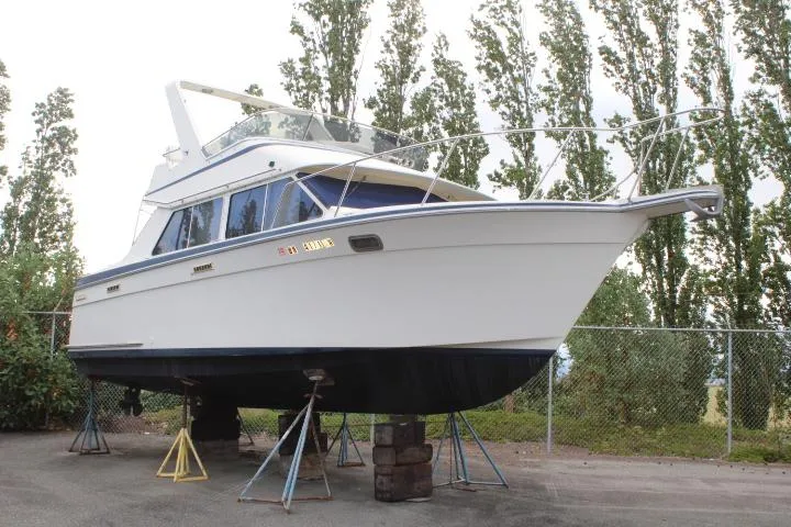 Slide: The Image of 1990 Tollycraft Sport Sedan boat on stands, surrounded by trees and fencing. - 6