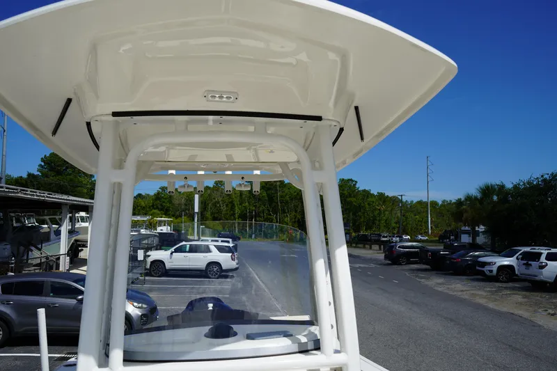 Slide: The Image of 2021 Robalo R230 Center Console boat with T-top, parked in a lot under clear blue sky. - 24