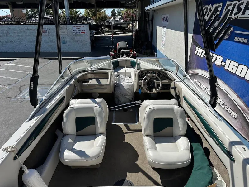 Slide: The Image of 2001 Reinell 203 boat interior with white seating and steering wheel, parked outdoors. - 12