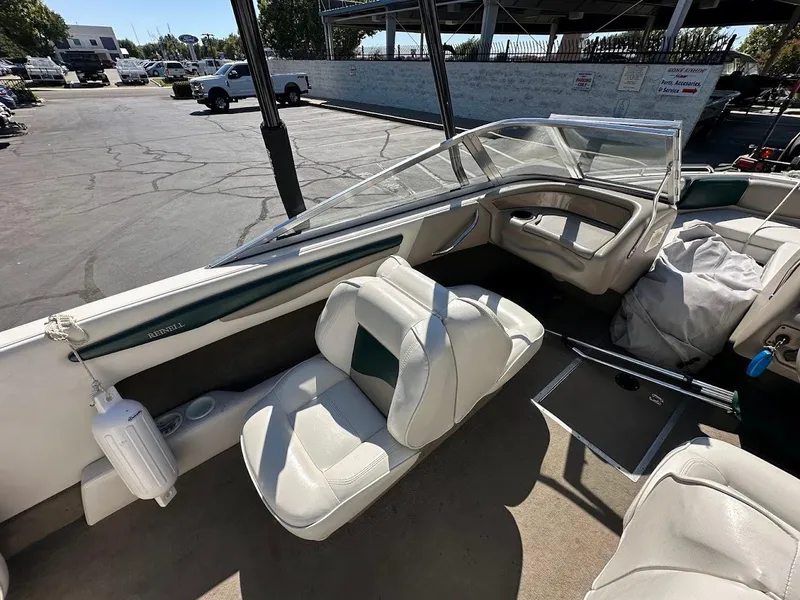 Slide: The Image of 2001 Reinell 203 boat interior with white seating and windshield in a parking lot. - 15
