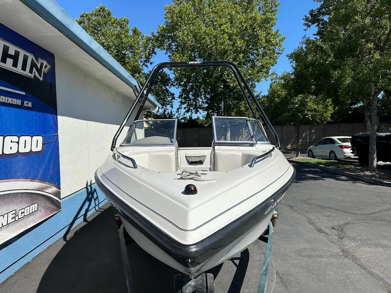 Slide: The Image of 2001 Reinell 203 boat parked outdoors, surrounded by trees and a building. - 3