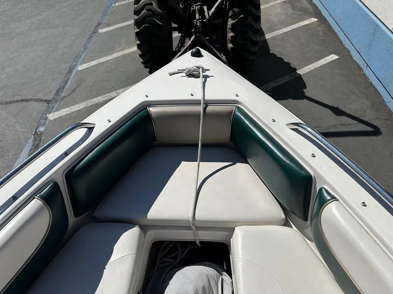 Slide: The Image of Bow of a 2001 Reinell 203 boat with green and white seating, parked on pavement. - 30