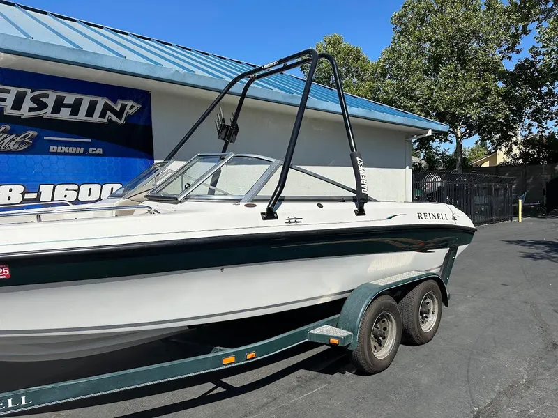 Slide: The Image of 2001 Reinell 203 boat on trailer, parked outside a building with blue roof. - 6