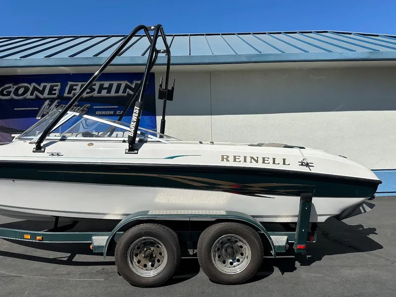 Slide: The Image of 2001 Reinell 203 boat on trailer, parked outside a building with blue roof. - 7