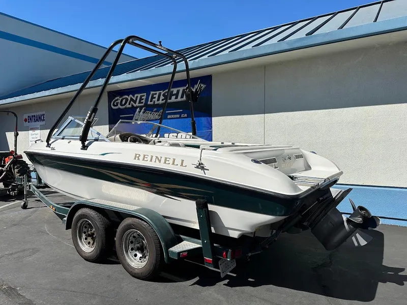 Slide: The Image of 2001 Reinell 203 boat on trailer, parked outside a building with a blue roof. - 8