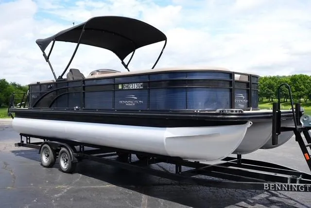 Slide: The Image of 2019 Bennington 25' Pontoon boat on trailer, featuring a sleek design and canopy. - 2