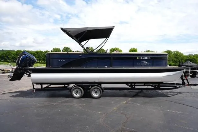 Slide: The Image of 2019 Bennington 25' Pontoon boat on trailer, black canopy, parked outdoors. - 3
