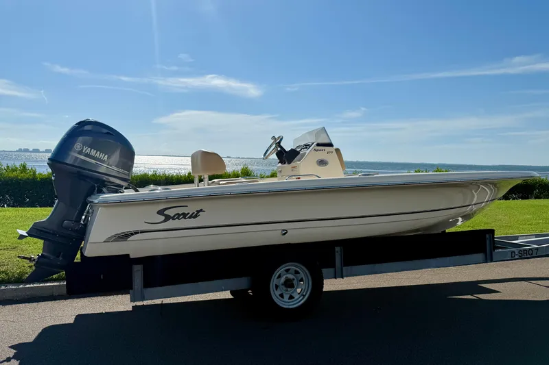 Slide: The Image of 2026 Scout 177 Sport boat on trailer with Yamaha engine, parked by waterfront. - 1