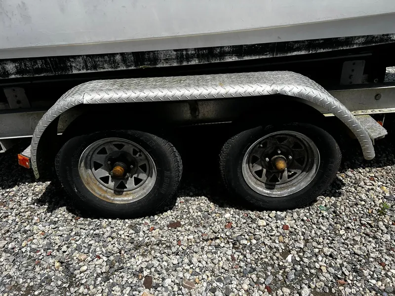 Slide: The Image of Trailer wheels of a 1997 Boston Whaler 20 Dauntless on gravel surface. - 19