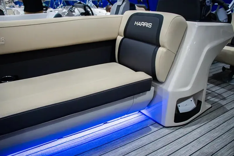 Slide: The Image of 2024 Harris Cruiser 230 boat interior with beige and black seating, featuring blue LED lighting. - 10