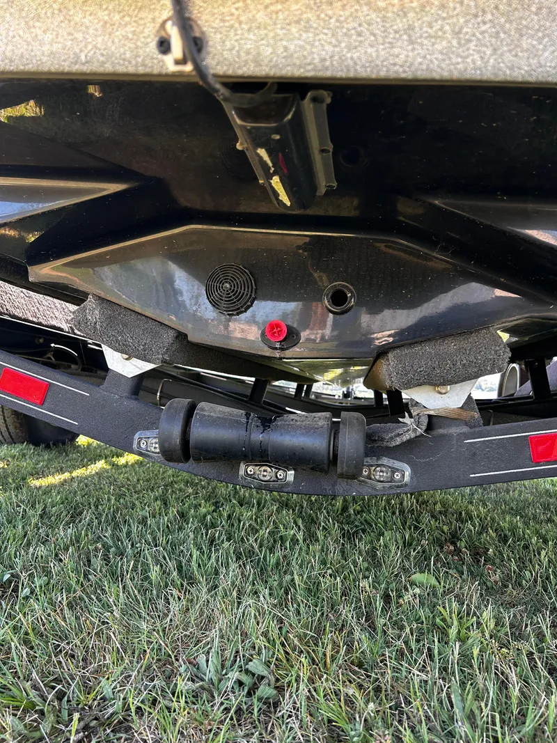 Slide: The Image of 2024 Ranger Z519 boat trailer underside on grass, showing hull and roller details. - 20