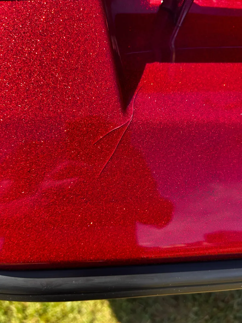 Slide: The Image of Close-up of a 2024 Ranger Z519 with red metallic paint and visible surface damage. - 23