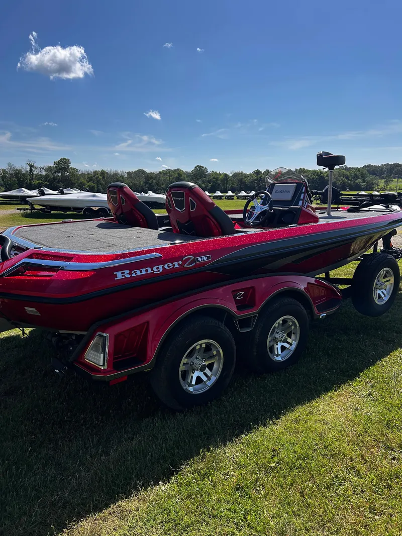 Slide: The Image of 2024 Ranger Z519 boat in vibrant red, parked on grass under a clear blue sky. - 24